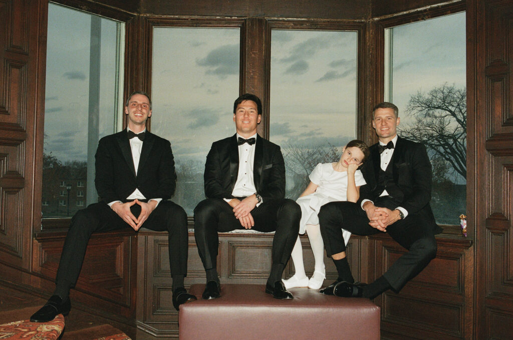 groomsmen and flower girls sitting on a bench on 35mm film